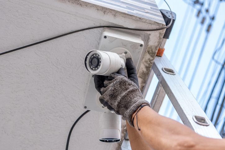 Technician installing a security camera on an exterior wall